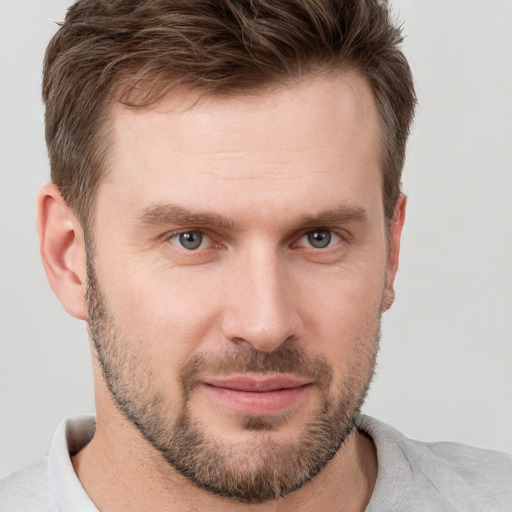 Joyful white young-adult male with short  brown hair and grey eyes