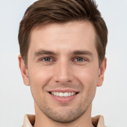 Joyful white young-adult male with short  brown hair and grey eyes