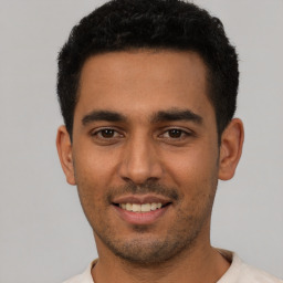 Joyful latino young-adult male with short  black hair and brown eyes