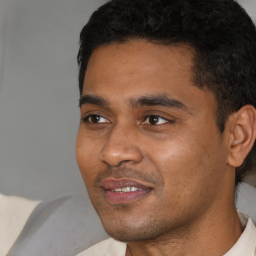 Joyful black young-adult male with short  black hair and brown eyes