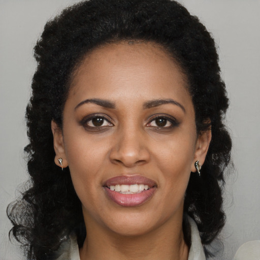Joyful black young-adult female with long  black hair and brown eyes