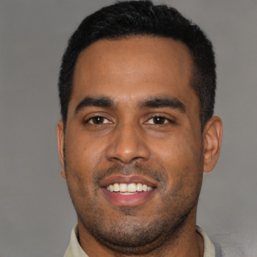 Joyful black young-adult male with short  black hair and brown eyes
