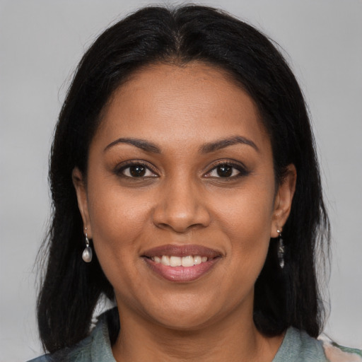Joyful black young-adult female with long  brown hair and brown eyes