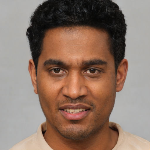 Joyful black young-adult male with short  black hair and brown eyes