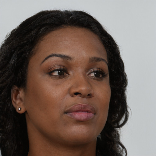 Joyful black young-adult female with long  brown hair and brown eyes