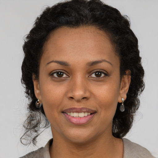 Joyful black young-adult female with long  brown hair and brown eyes