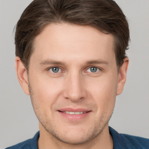 Joyful white young-adult male with short  brown hair and grey eyes