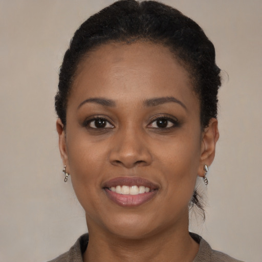 Joyful black young-adult female with short  black hair and brown eyes