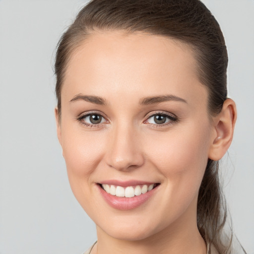 Joyful white young-adult female with medium  brown hair and grey eyes