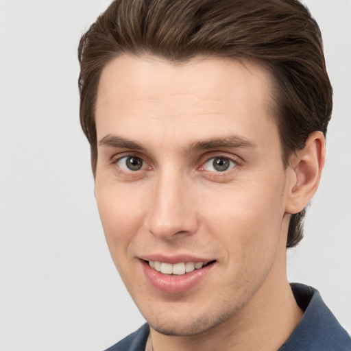 Joyful white young-adult male with short  brown hair and grey eyes