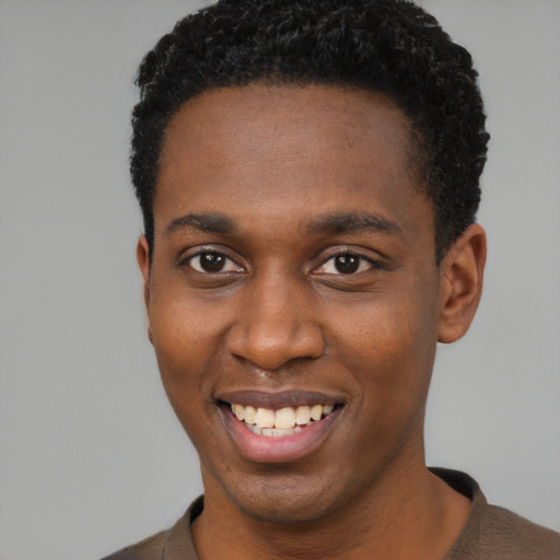 Joyful black young-adult male with short  brown hair and brown eyes