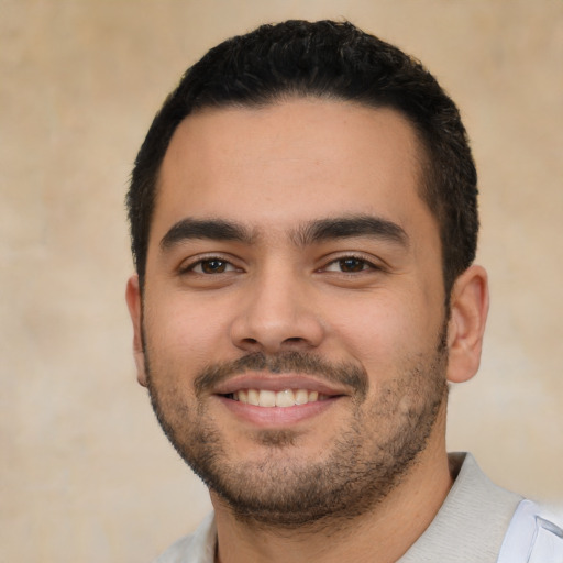 Joyful latino young-adult male with short  black hair and brown eyes