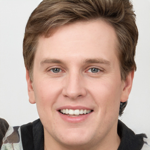 Joyful white young-adult male with short  brown hair and grey eyes