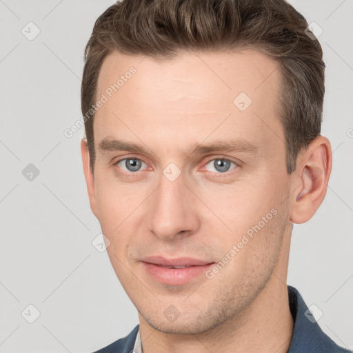 Joyful white young-adult male with short  brown hair and grey eyes