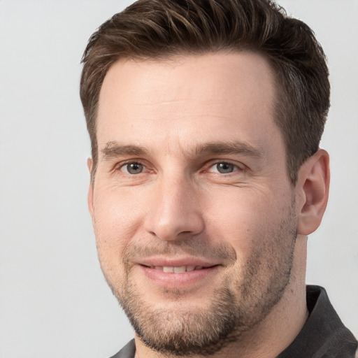 Joyful white young-adult male with short  brown hair and grey eyes