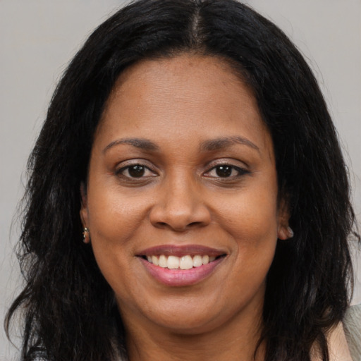 Joyful black adult female with long  brown hair and brown eyes