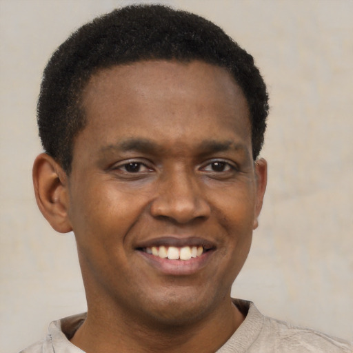 Joyful black young-adult male with short  brown hair and brown eyes