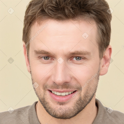 Joyful white young-adult male with short  brown hair and grey eyes