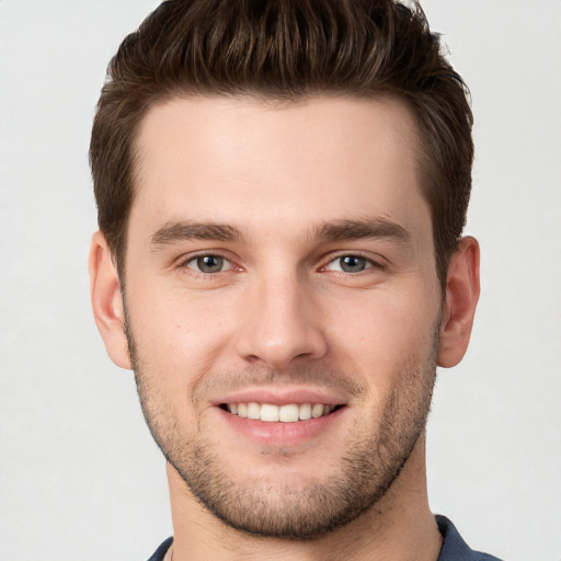 Joyful white young-adult male with short  brown hair and grey eyes