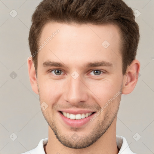 Joyful white young-adult male with short  brown hair and grey eyes