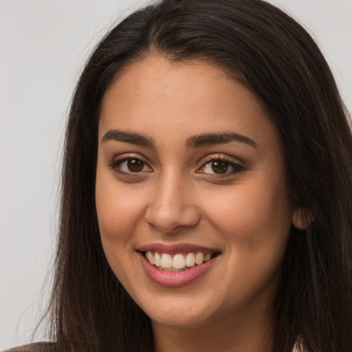 Joyful latino young-adult female with long  brown hair and brown eyes