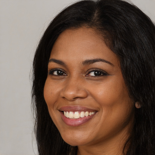 Joyful black young-adult female with long  black hair and brown eyes