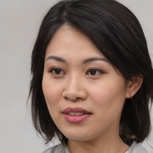 Joyful asian adult female with medium  brown hair and brown eyes
