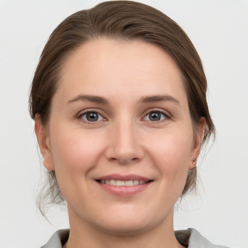 Joyful white young-adult female with medium  brown hair and grey eyes