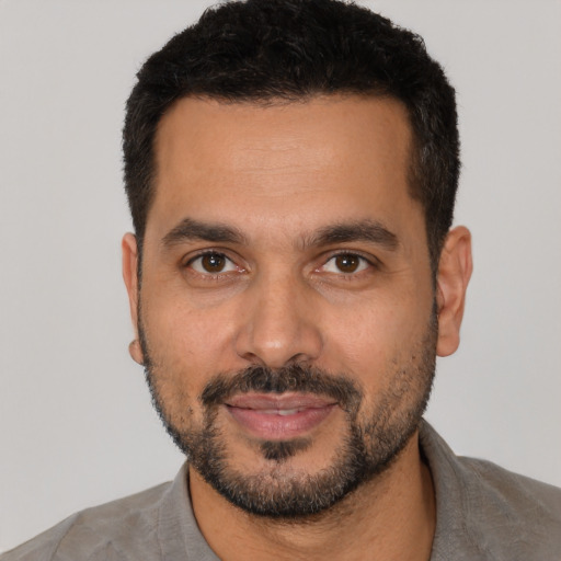 Joyful latino young-adult male with short  black hair and brown eyes