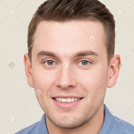 Joyful white young-adult male with short  brown hair and grey eyes