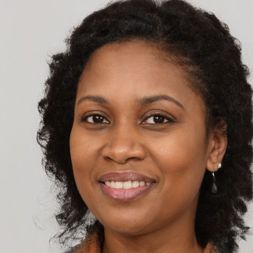 Joyful black young-adult female with long  brown hair and brown eyes