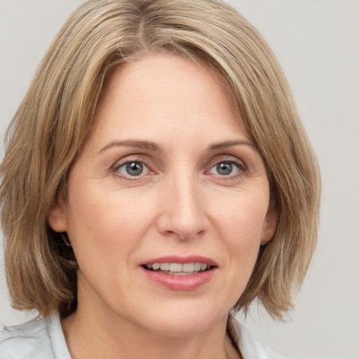 Joyful white adult female with medium  brown hair and blue eyes