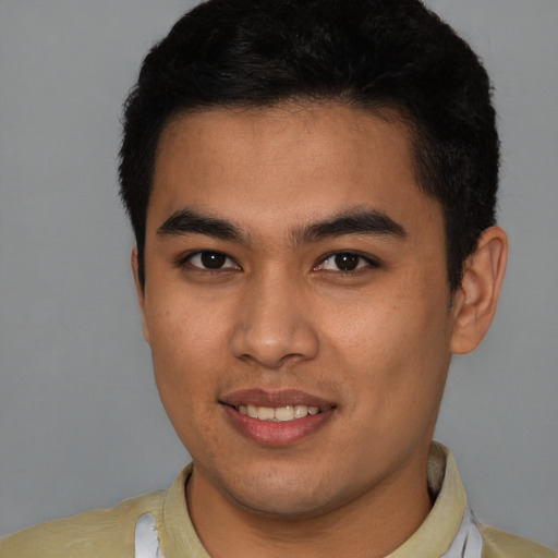 Joyful latino young-adult male with short  brown hair and brown eyes