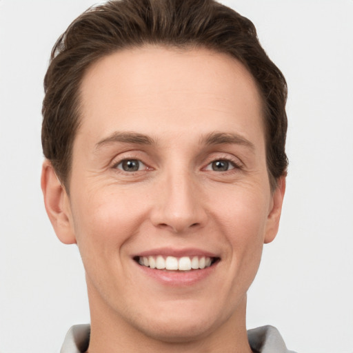 Joyful white young-adult male with short  brown hair and grey eyes