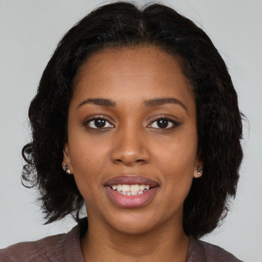 Joyful black young-adult female with long  black hair and brown eyes