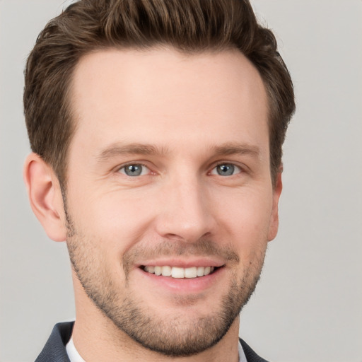 Joyful white young-adult male with short  brown hair and grey eyes