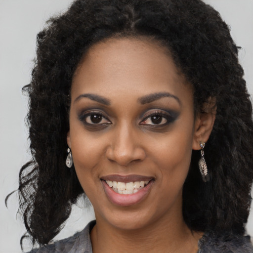 Joyful black young-adult female with long  black hair and brown eyes