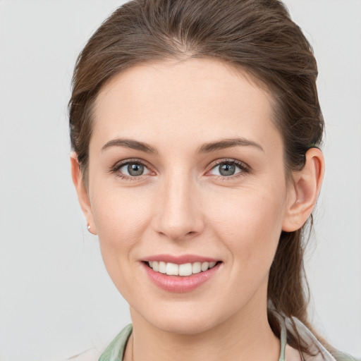 Joyful white young-adult female with medium  brown hair and grey eyes