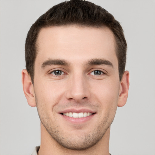 Joyful white young-adult male with short  brown hair and grey eyes