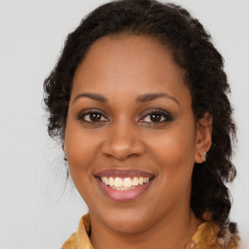 Joyful black young-adult female with long  brown hair and brown eyes