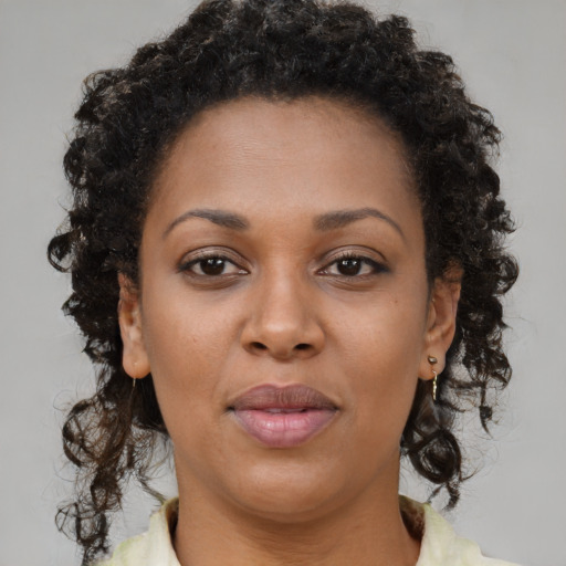 Joyful black young-adult female with long  brown hair and brown eyes