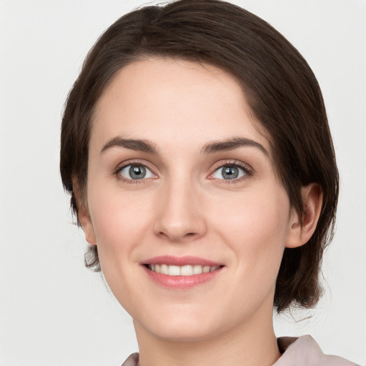 Joyful white young-adult female with medium  brown hair and grey eyes