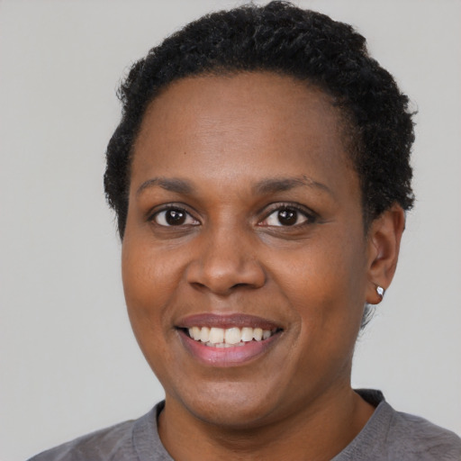 Joyful black young-adult female with short  black hair and brown eyes