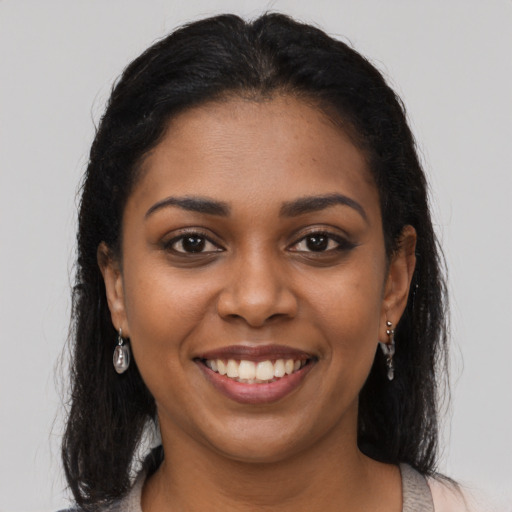 Joyful black young-adult female with long  brown hair and brown eyes