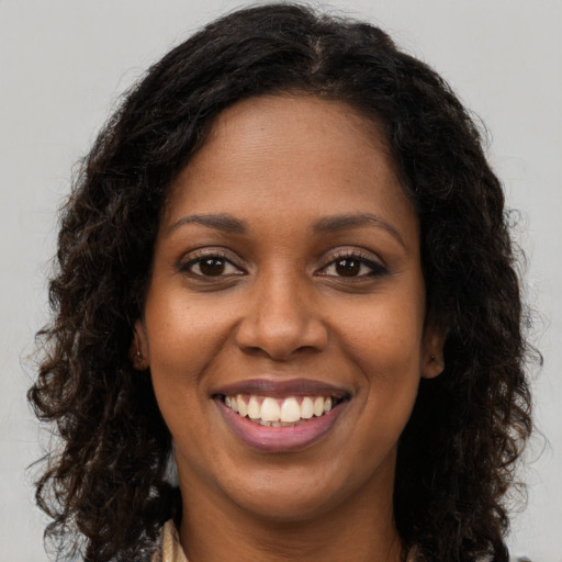 Joyful black young-adult female with long  brown hair and brown eyes