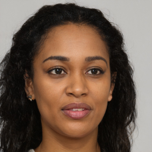 Joyful black young-adult female with long  brown hair and brown eyes