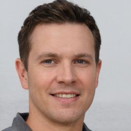 Joyful white young-adult male with short  brown hair and grey eyes