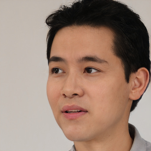 Joyful asian young-adult male with short  black hair and brown eyes