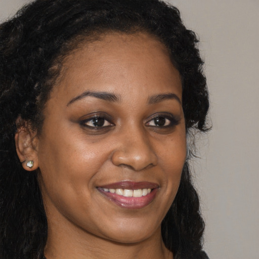 Joyful black young-adult female with long  brown hair and brown eyes