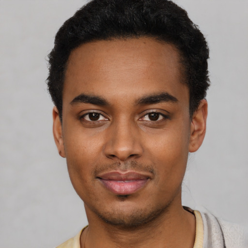Joyful black young-adult male with short  black hair and brown eyes